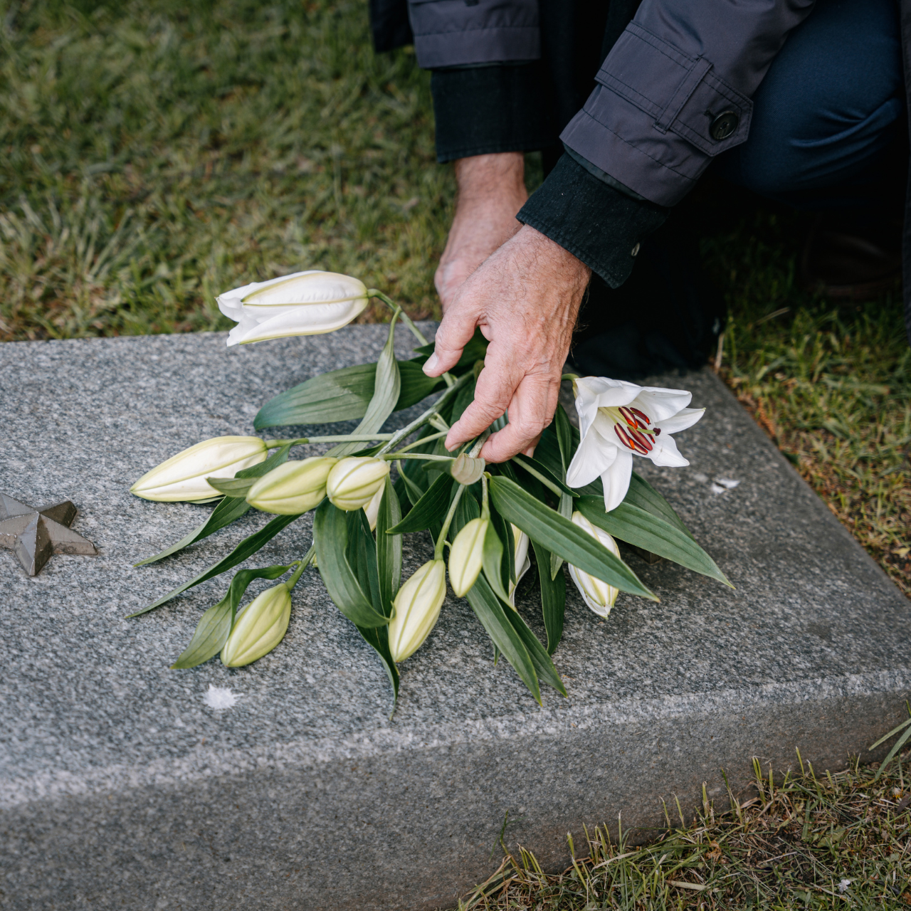 A Person Putting Flowers on a Headstone